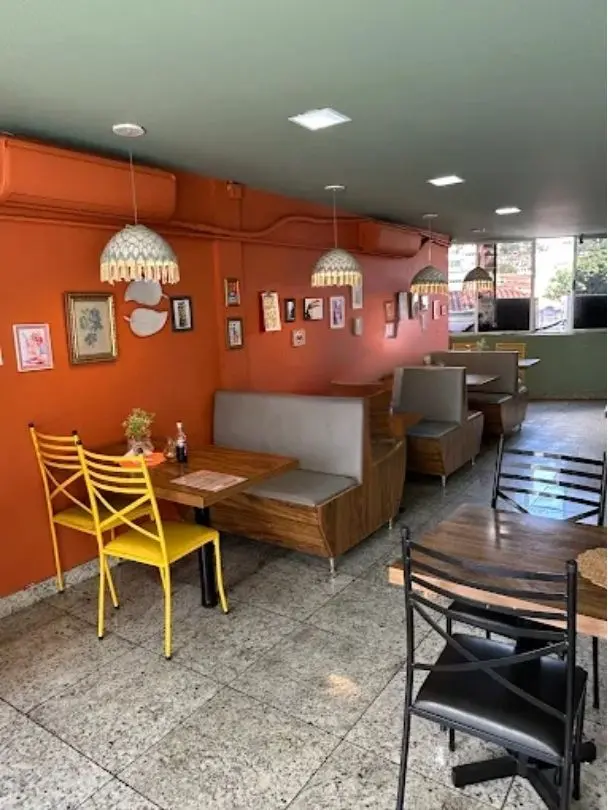 Área acolhedora real do Bistrô Menu com poltronas e mesas